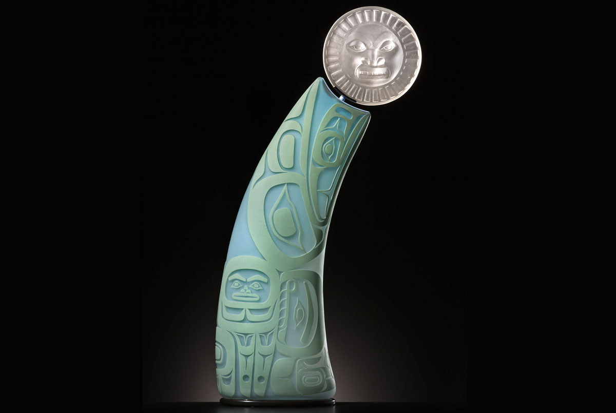 A sculpture of the sun with figures below it
