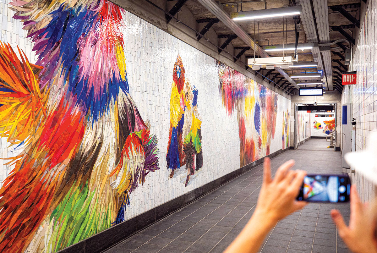 Person taking a photo of the mosaic characters on the subway walls