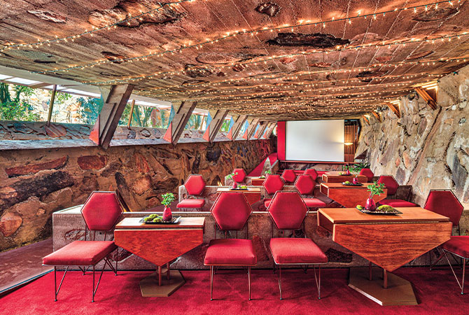 Enlargeable photo of red chairs and wooden tables in a room with stone walls
