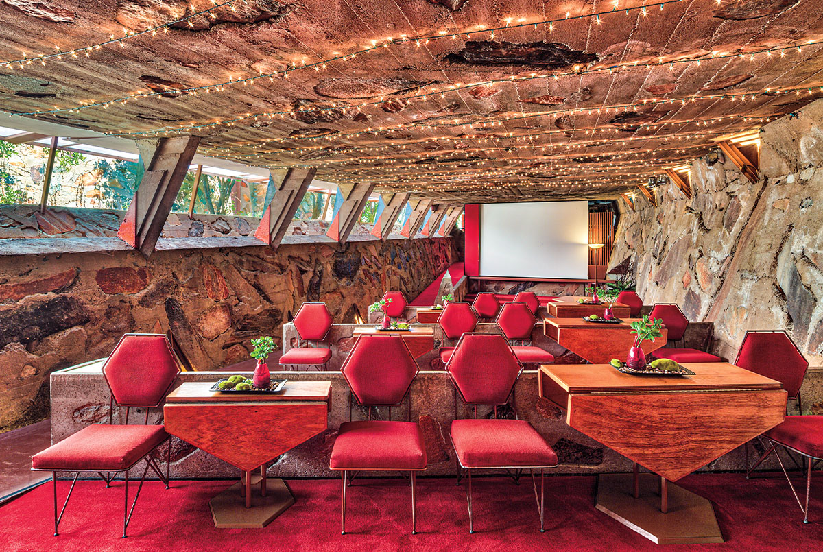 Red chairs and wooden tables in a room with stone walls