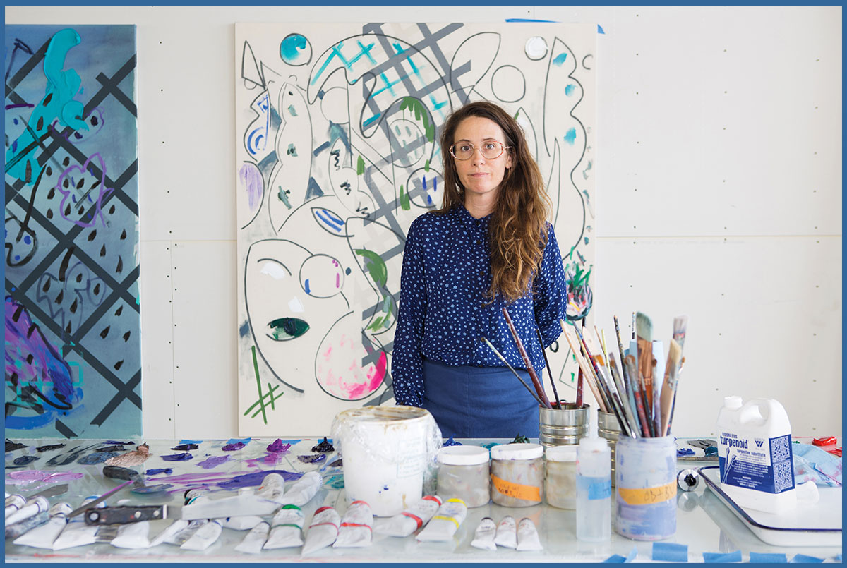 Person wearing all blue standing in front of an abstract painting