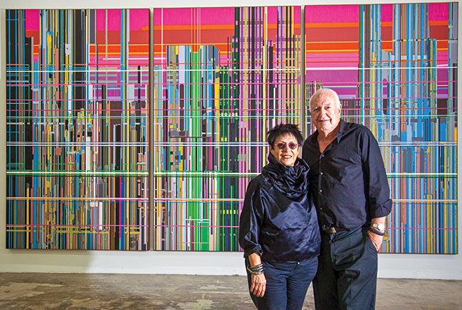 Enlargeable image of two art collectors posing in front of a colorful background