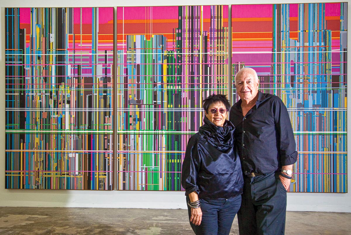 Image of two art collectors posing in front of a colorful background