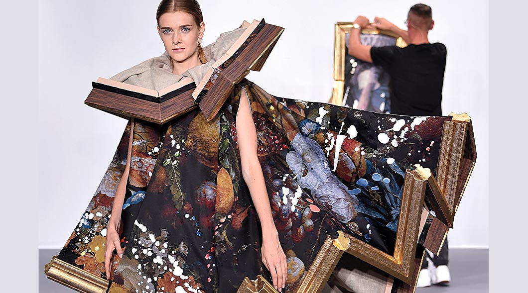 Image of a model walking a runway wearing clothing that looks like a deconstructed painting