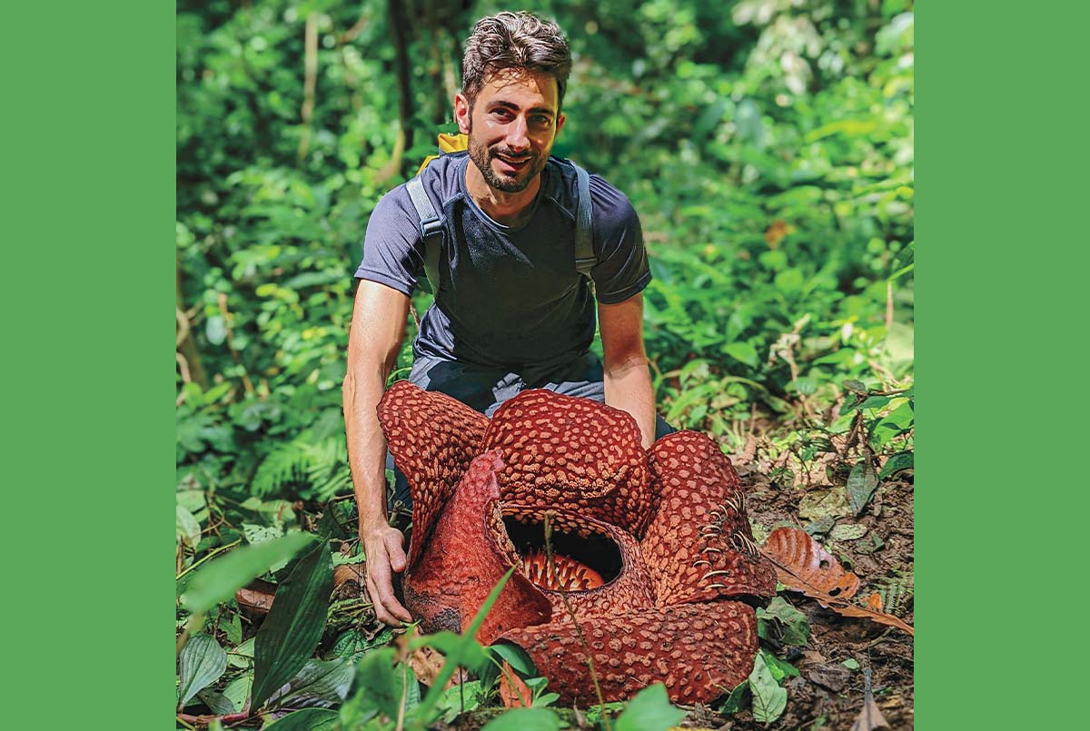 Image of a person posing with a large red-petal flower