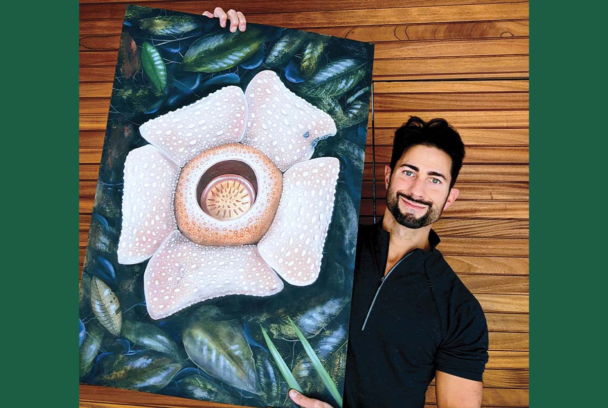 Image of a painter holding up their painting of a large flower