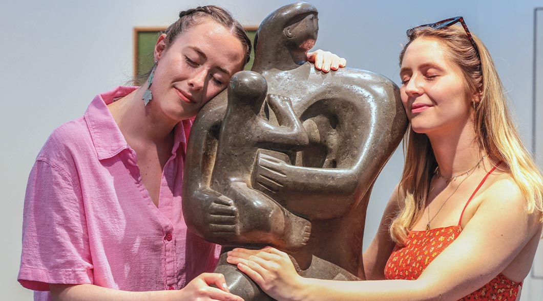 Image of two people hugging a statue of people hugging